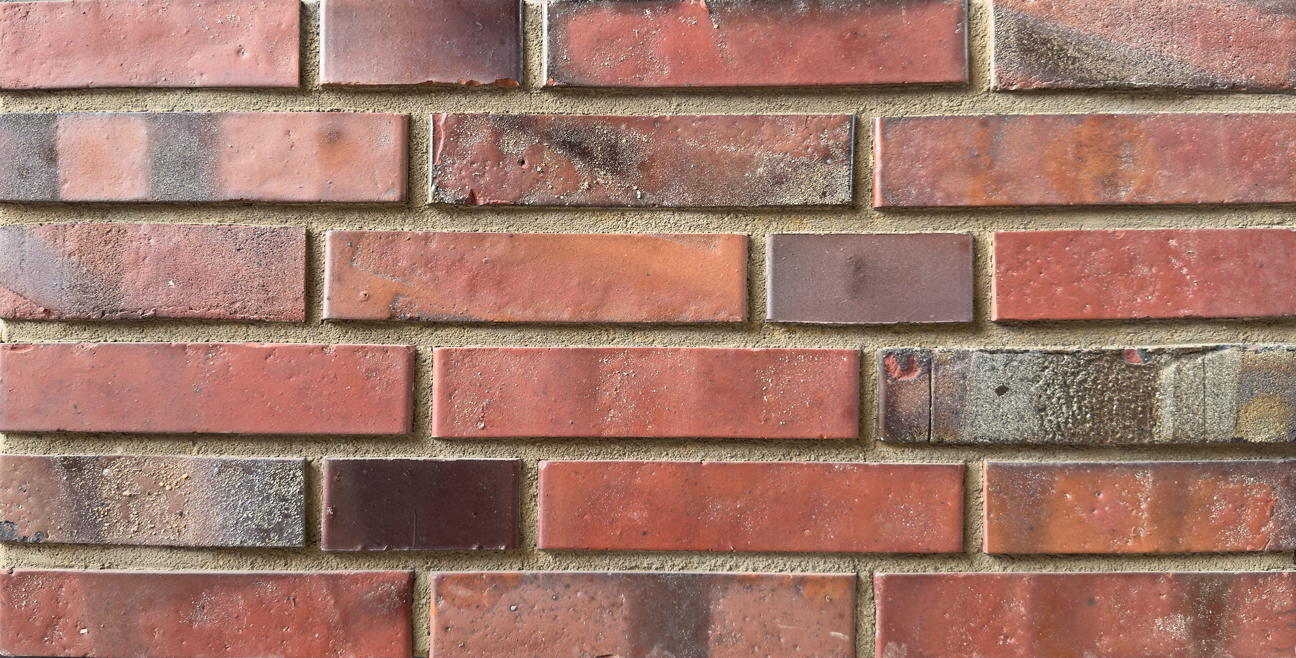 Mustertafel mit roten und braunen Klinkern, teilweise mit dunklen Stellen und Rückseiten Streifen