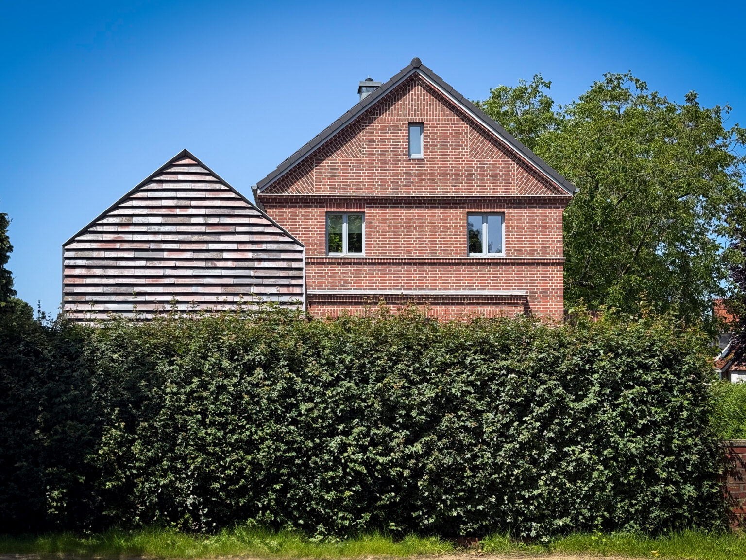 Fronatansicht auf den Anbau mit Keramikschindeln CradleTop CTP Danzig in rot-braun mit Kohleaufbrennungen und das Originalhaus