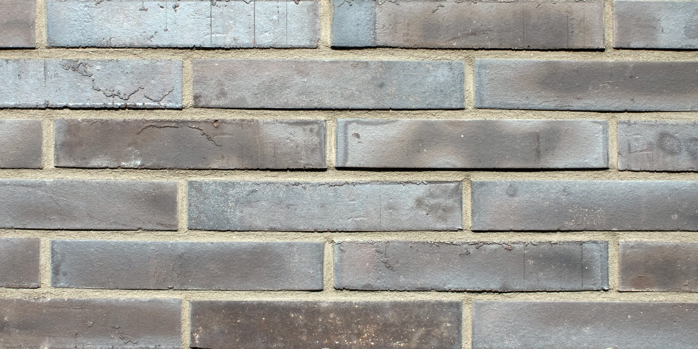 Mustertafel mit 6 Reihen grau-anthrazit farbener Riemchen mit leicht glänzenden Aufbrennungen